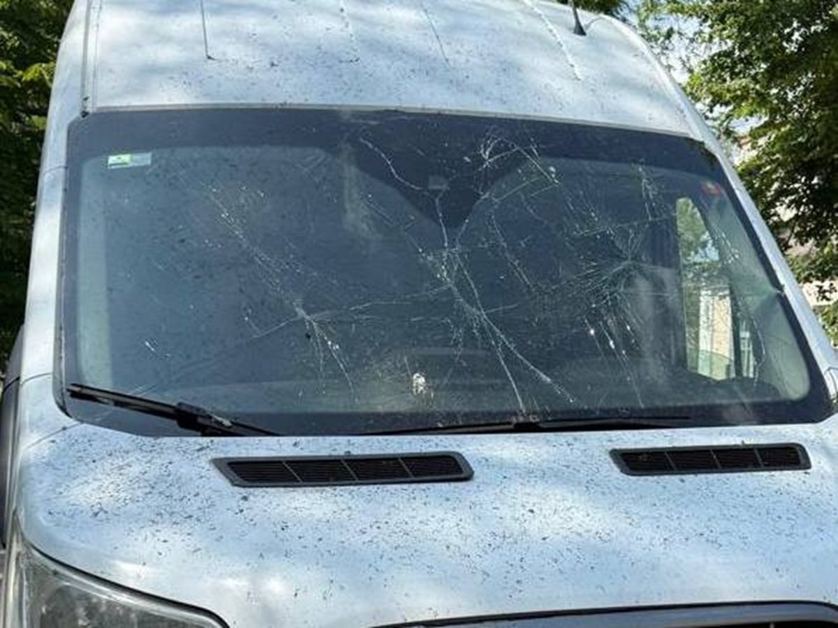 Пошкоджений багатоповерховий будинок і мікроавтобус після ракетного удару на Дніпропетровщині.