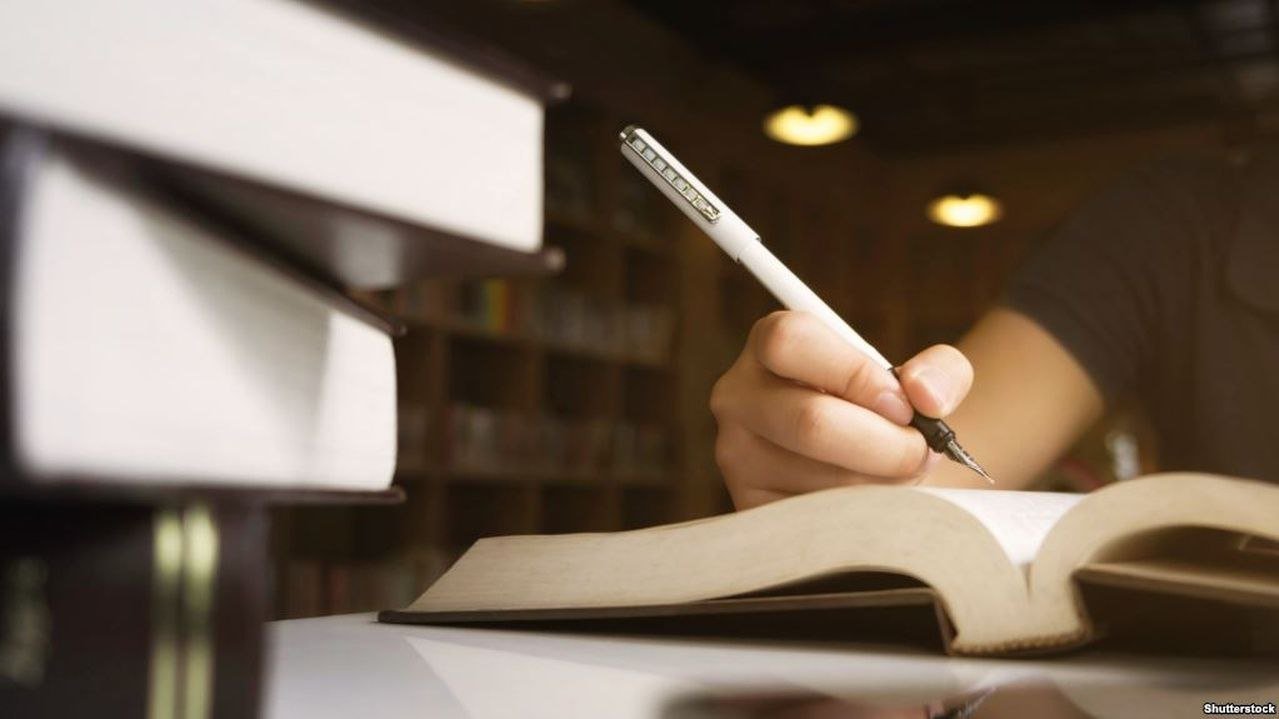 Людина пише в книзі