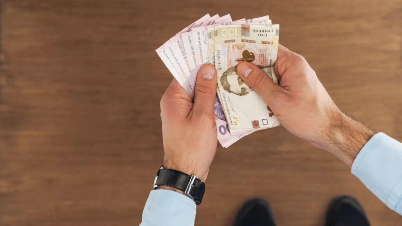 Чоловік тримає гроші в руках