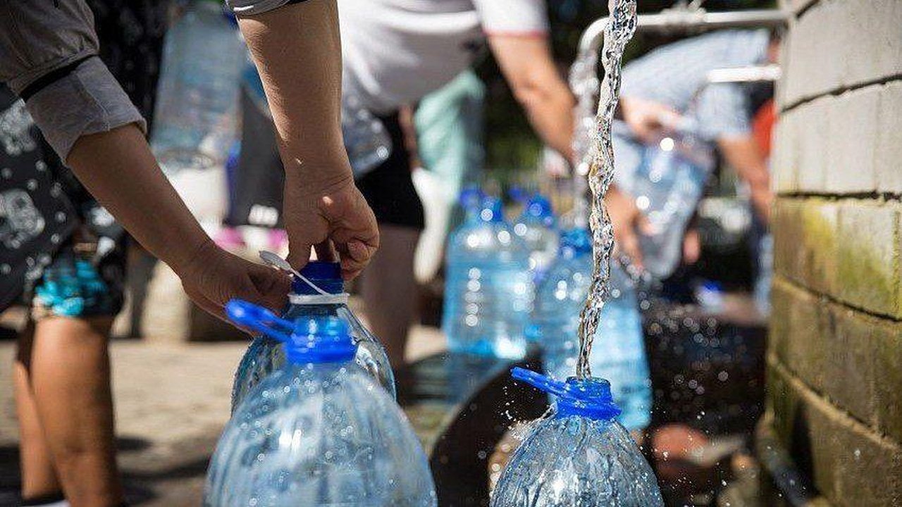 Люди набирають воду в пляшки